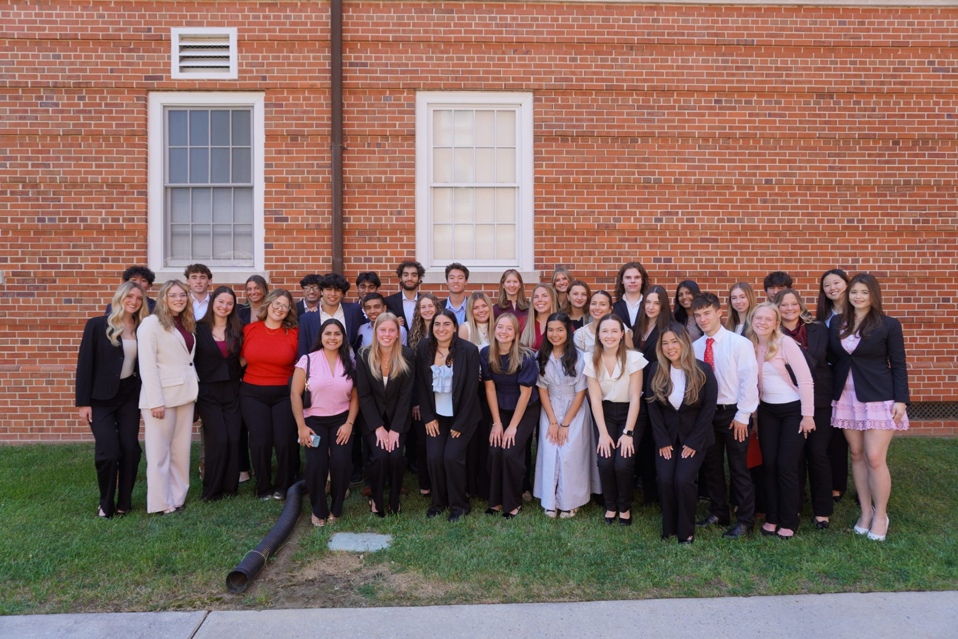 Alpha Epsilon Delta chapter members gathered outside a brick building on campus