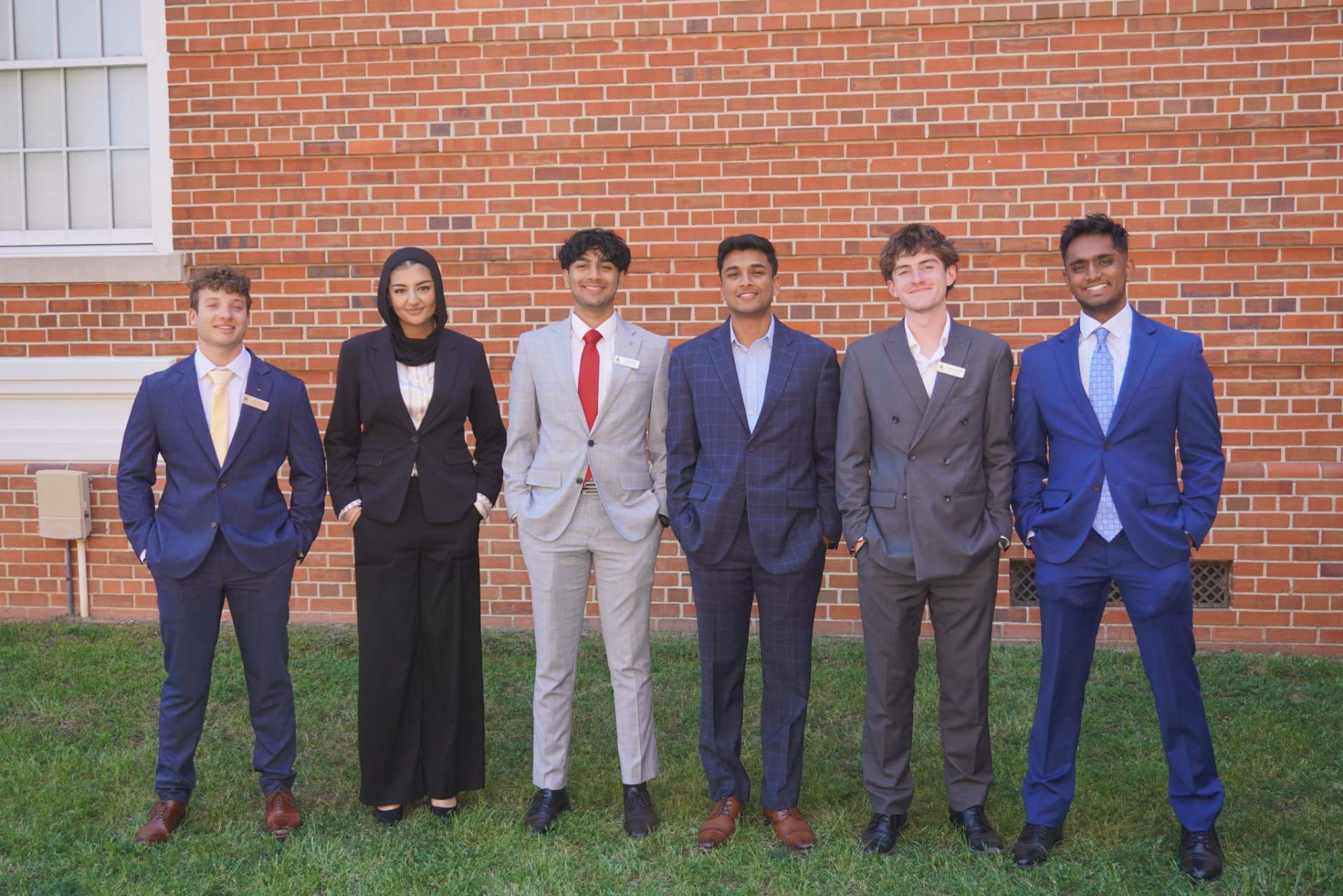 AED leadership team members in business attire outside a brick building on campus