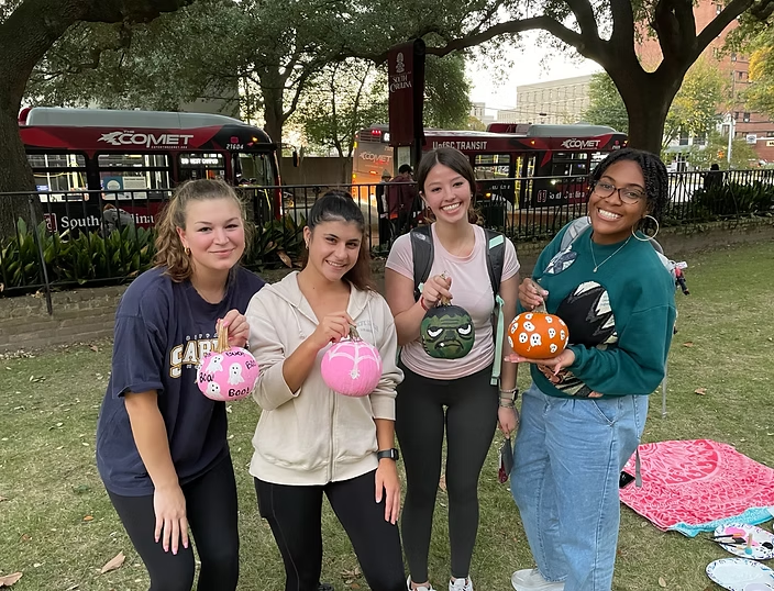 Members showing off their painted pumpkins on campus