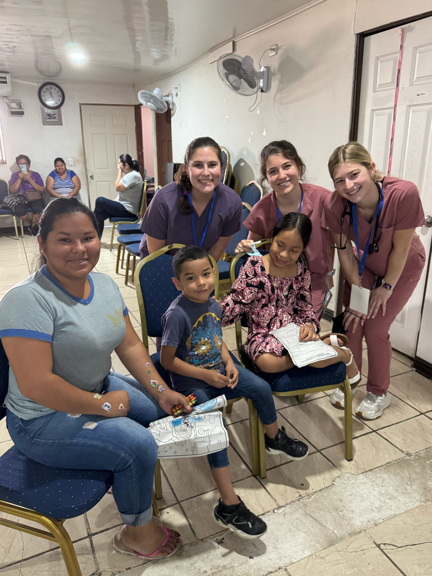 AED members in scrubs with a family at a community clinic