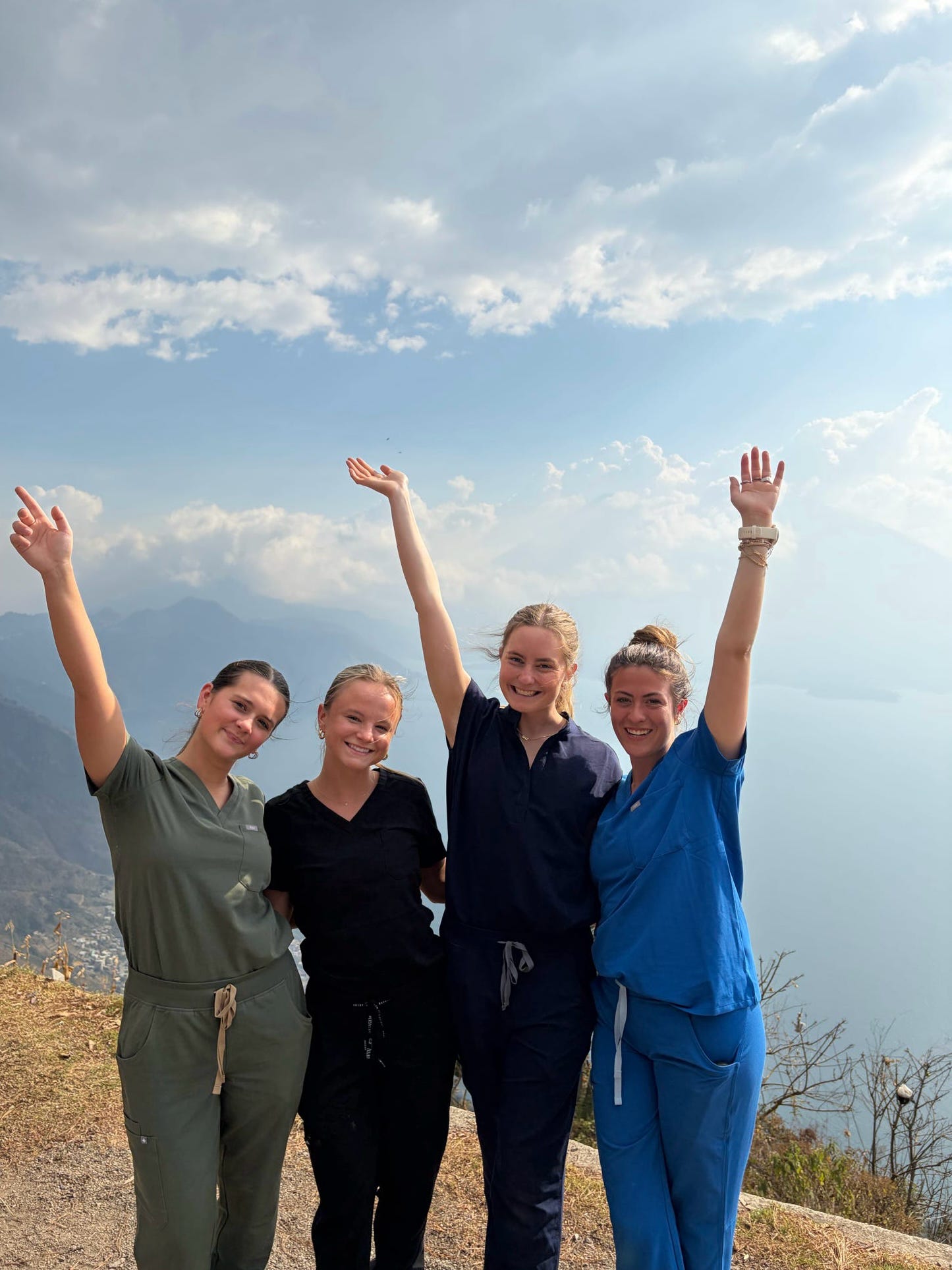 AED members in scrubs cheering on a mountain overlook above a lake