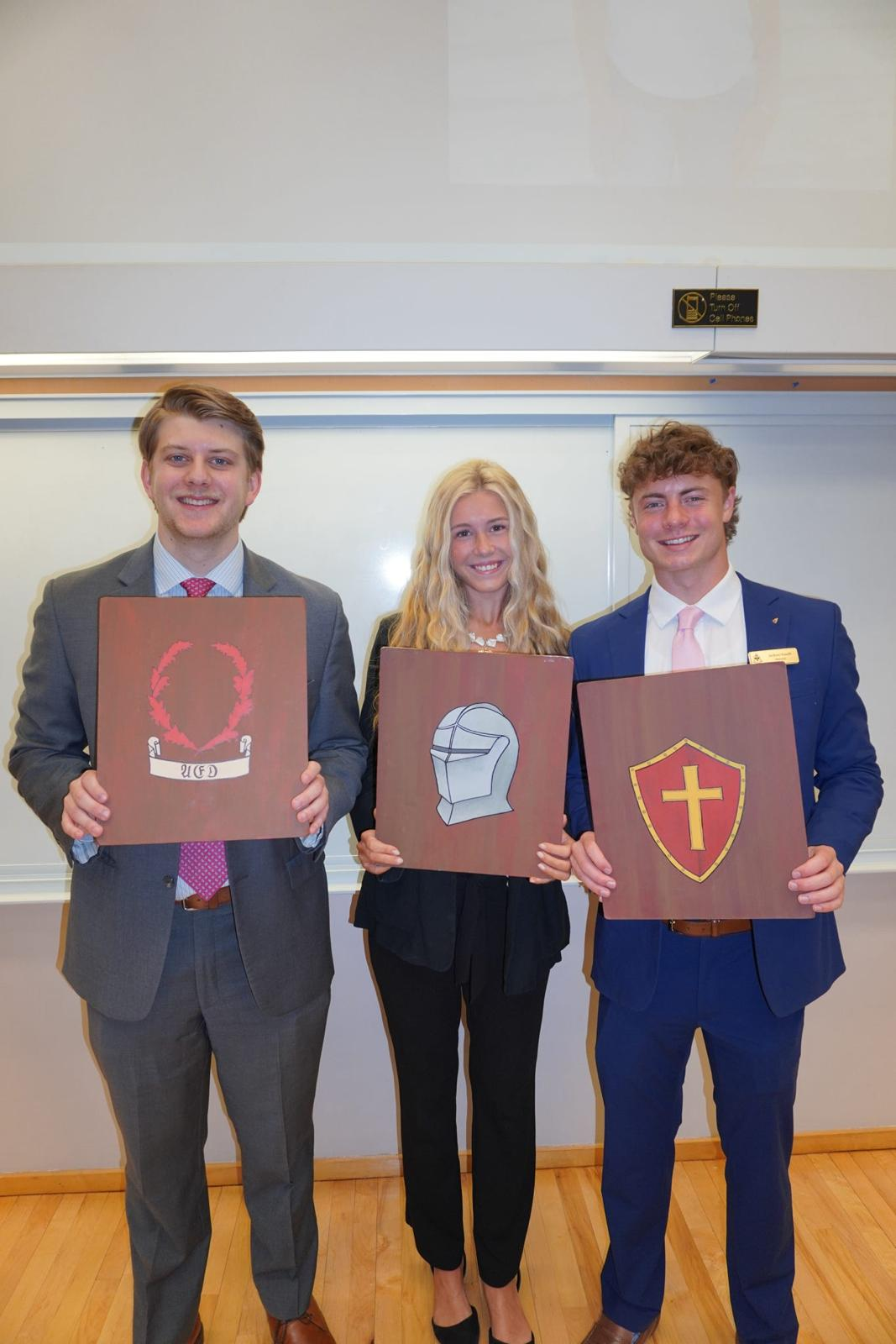 Members presenting hand-painted crest boards at chapter