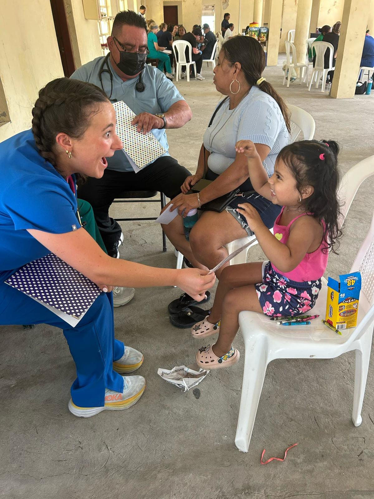 AED member in scrubs playing with a young child at a medical mission clinic