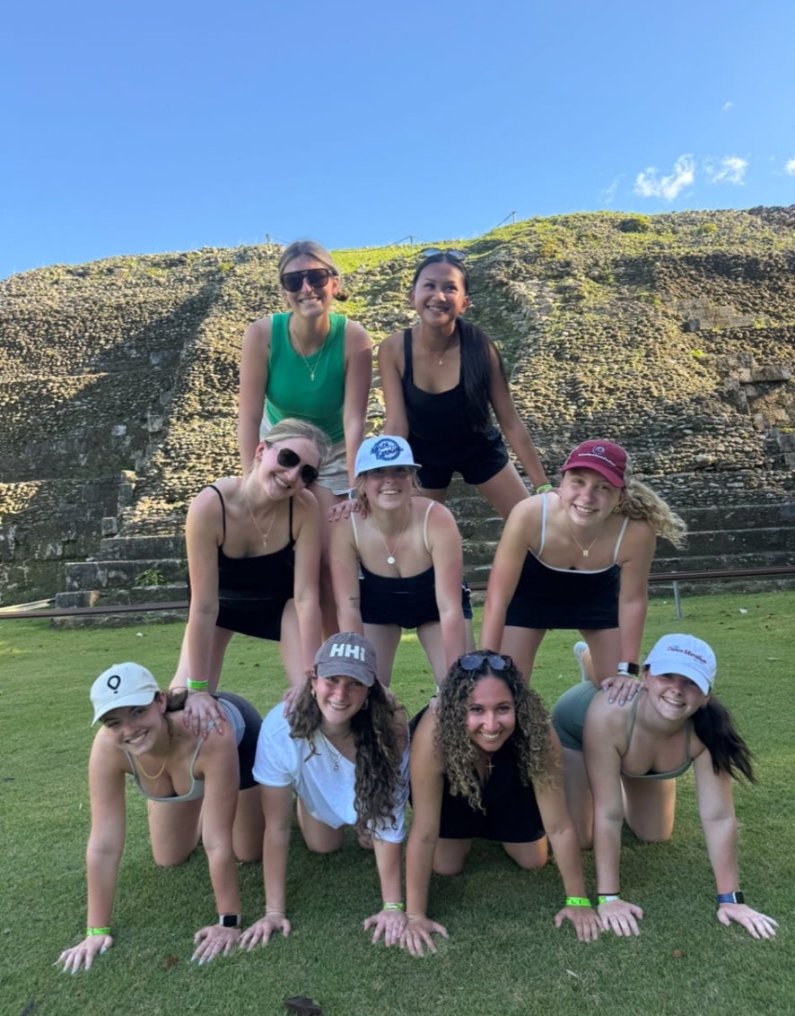 Members making a pyramid at a Mayan ruin