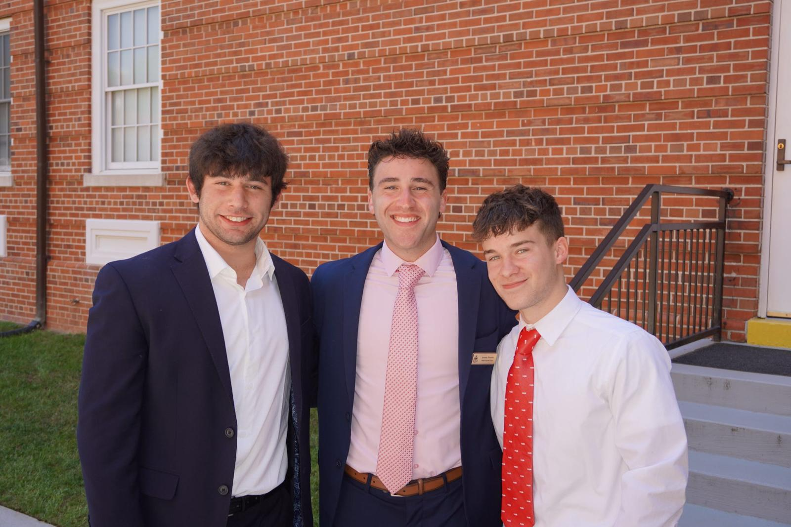 Three AED members in professional attire outside a brick building