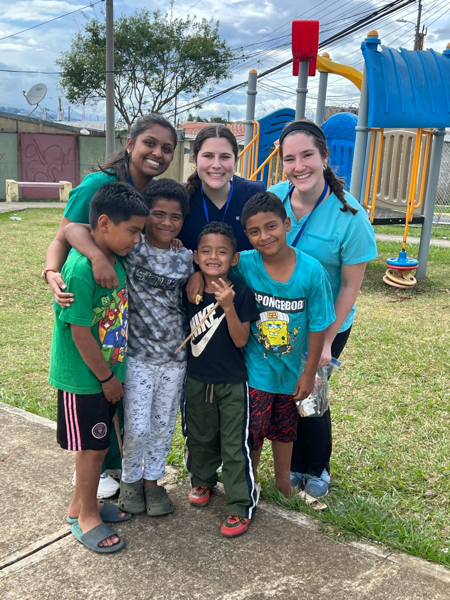 AED members in scrubs with children during an international service trip